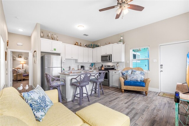 kitchen featuring white cabinetry, appliances with stainless steel finishes, light hardwood / wood-style floors, and a breakfast bar