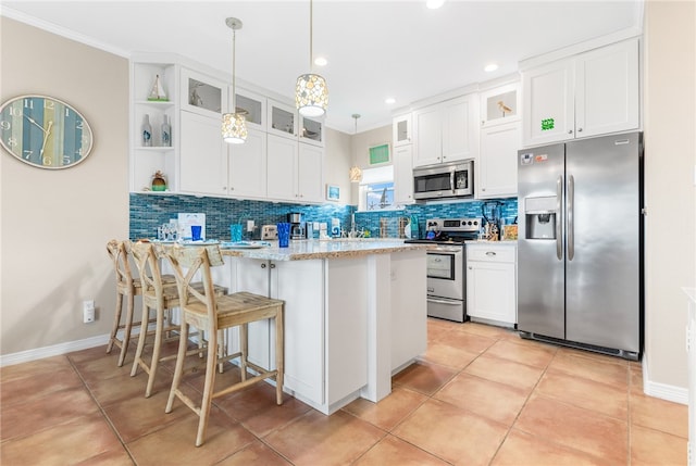 kitchen with a kitchen bar, stainless steel appliances, white cabinets, decorative backsplash, and pendant lighting