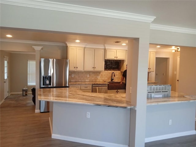 kitchen with stainless steel appliances, dark wood-type flooring, kitchen peninsula, crown molding, and white cabinetry