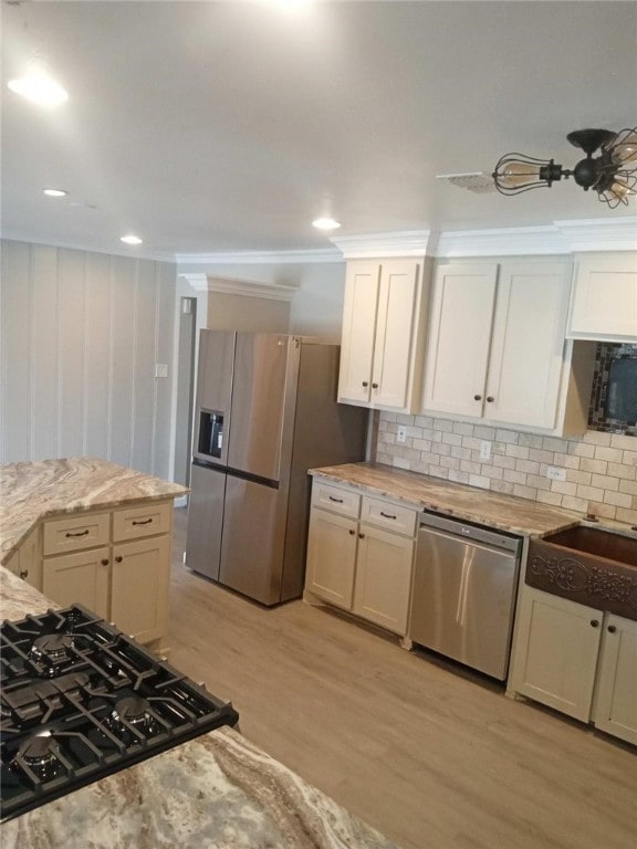 kitchen with light hardwood / wood-style floors, black appliances, tasteful backsplash, crown molding, and light stone countertops