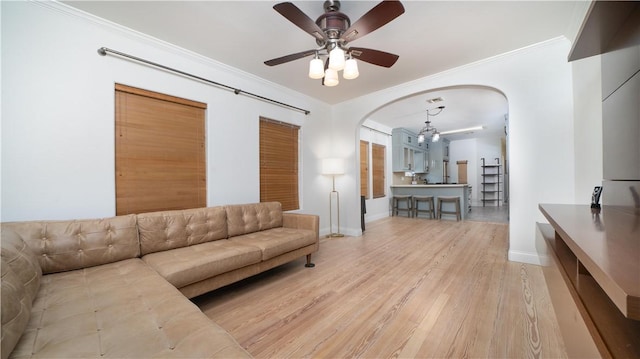 living room with arched walkways, ornamental molding, baseboards, and light wood-type flooring