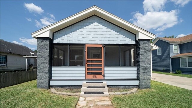 bungalow with a sunroom, fence, and a front lawn