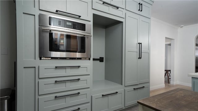 kitchen with baseboards, ornamental molding, and oven