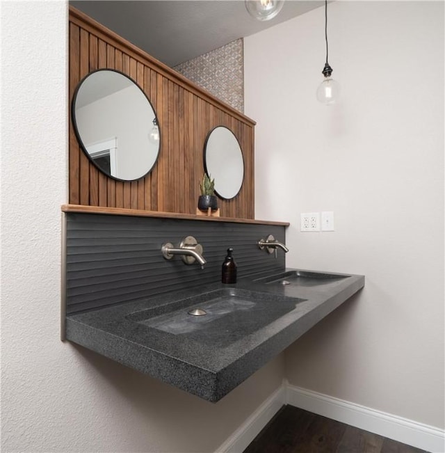 bathroom with baseboards, wood finished floors, and a sink