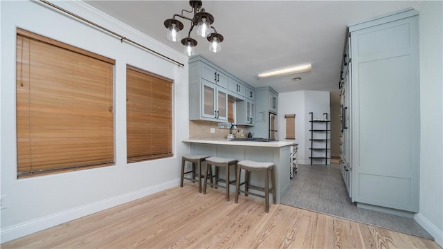 kitchen with light countertops, tasteful backsplash, a breakfast bar, a peninsula, and light wood-style floors