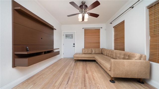 living area featuring baseboards, ornamental molding, light wood-style flooring, and a ceiling fan