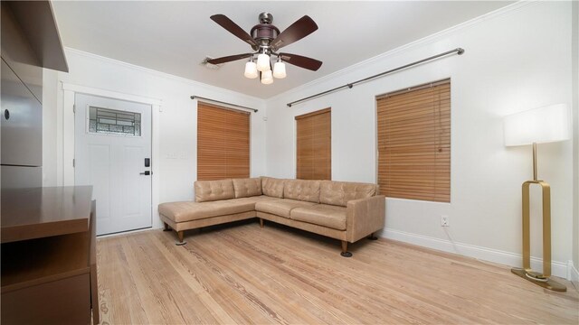 living area with light wood finished floors, baseboards, ceiling fan, and ornamental molding