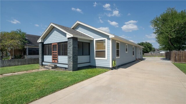 bungalow with driveway, a front yard, a sunroom, and fence