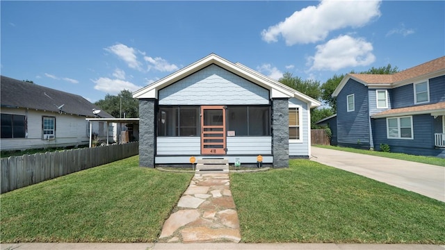 bungalow-style house featuring a front lawn, a sunroom, and fence
