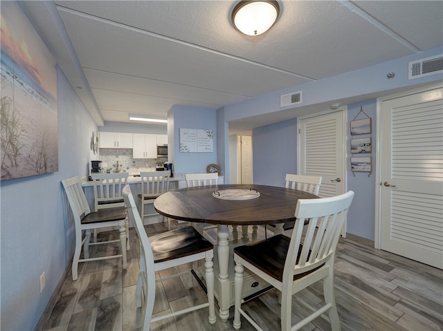 dining space with a textured ceiling and light hardwood / wood-style flooring