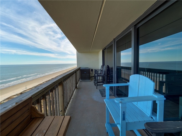 balcony with a view of the beach, a water view, and central AC