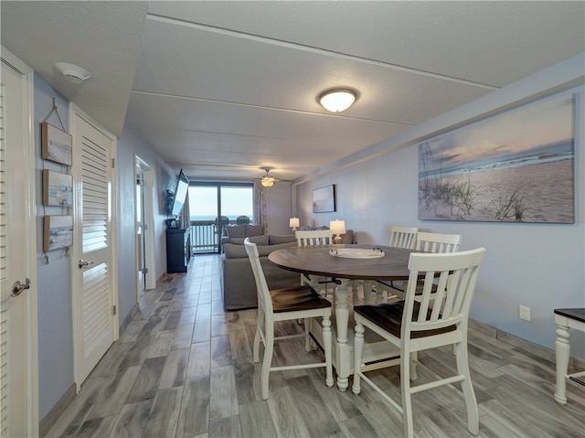 dining space featuring wood-type flooring, ceiling fan, and a textured ceiling