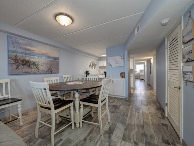 dining space with light hardwood / wood-style floors and a textured ceiling