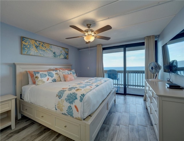 bedroom featuring a water view, multiple windows, ceiling fan, and access to exterior