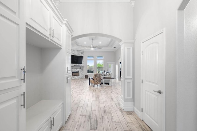 3726 Amanda Ln, Robstown, TX 78380 - mudroom featuring a ceiling fan, light wood finished floors, a fireplace, arched walkways, and a tray ceiling