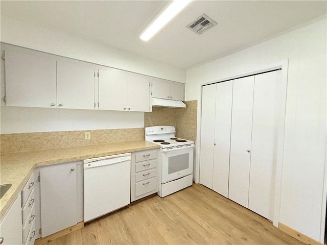 kitchen with under cabinet range hood, white appliances, visible vents, light countertops, and light wood finished floors