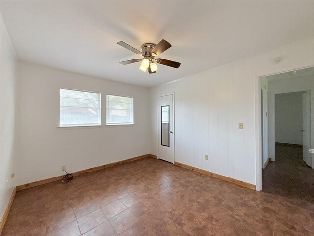 spare room featuring a ceiling fan and baseboards