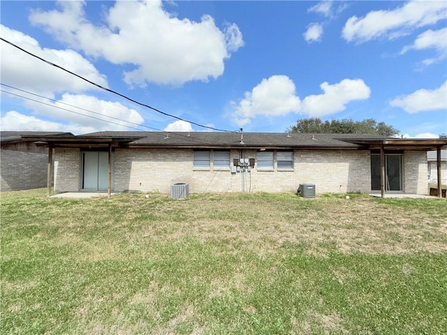 rear view of property with central AC, a lawn, and brick siding