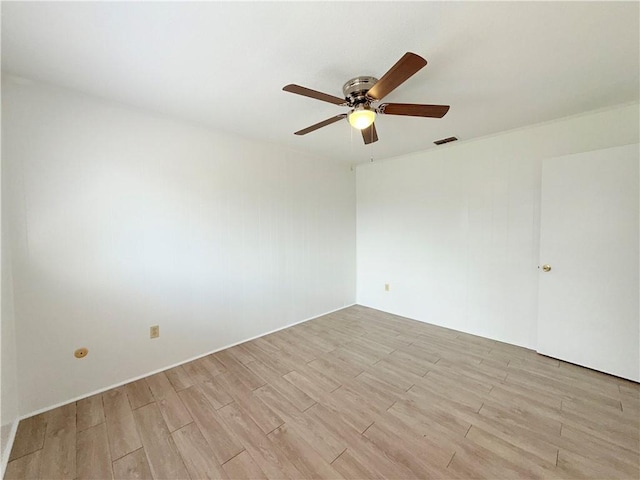 empty room featuring a ceiling fan, visible vents, and light wood finished floors