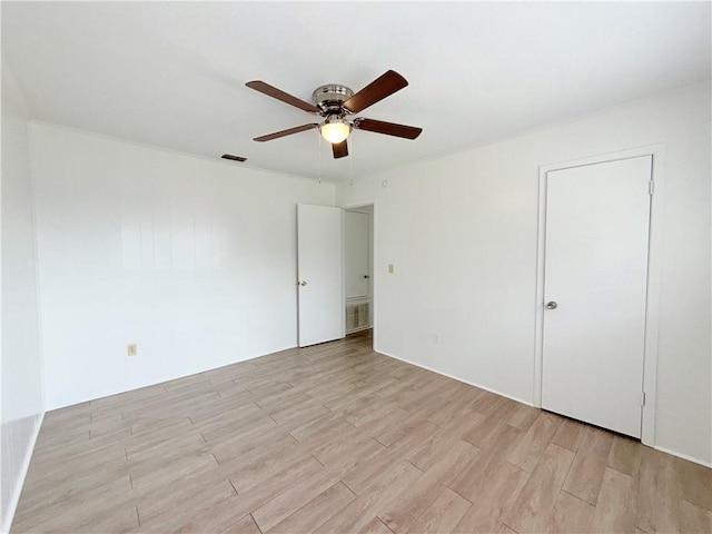 spare room with light wood-type flooring, visible vents, and ceiling fan