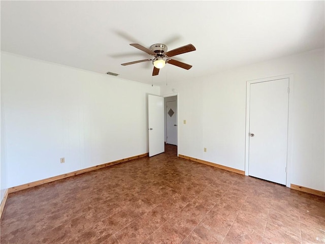 spare room with a ceiling fan, visible vents, and baseboards