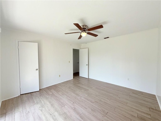 spare room featuring light wood-style flooring, visible vents, and a ceiling fan