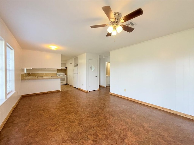 unfurnished living room with ceiling fan, a sink, visible vents, baseboards, and tile patterned floors