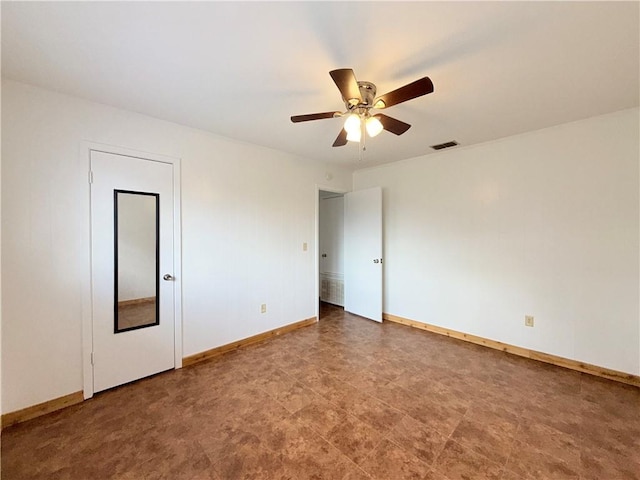 spare room with a ceiling fan, visible vents, and baseboards