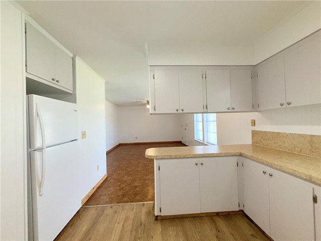 kitchen with light countertops, light wood finished floors, freestanding refrigerator, and white cabinetry