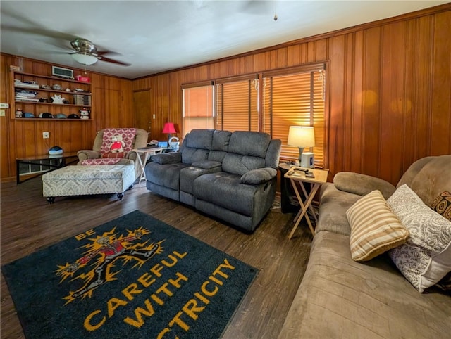 living room with dark wood-type flooring, wood walls, and ceiling fan