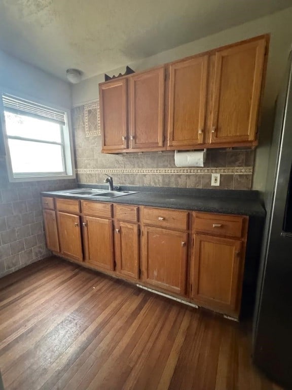 kitchen with dark countertops, dark wood-style flooring, brown cabinets, and a sink