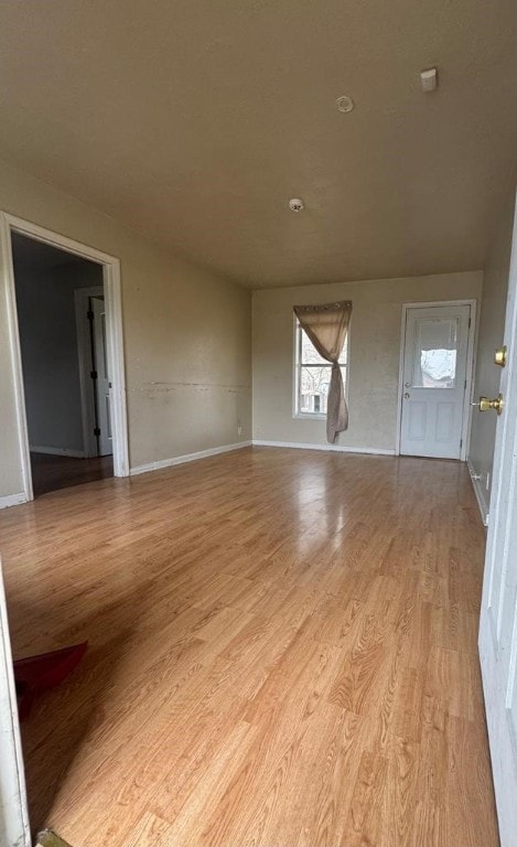 unfurnished living room featuring light wood finished floors and baseboards