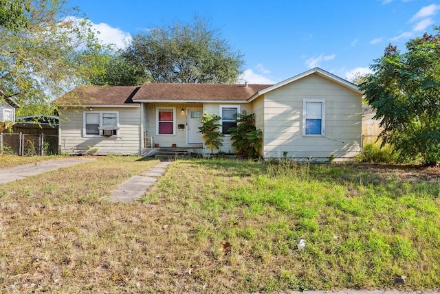 ranch-style home with fence, a front lawn, and cooling unit