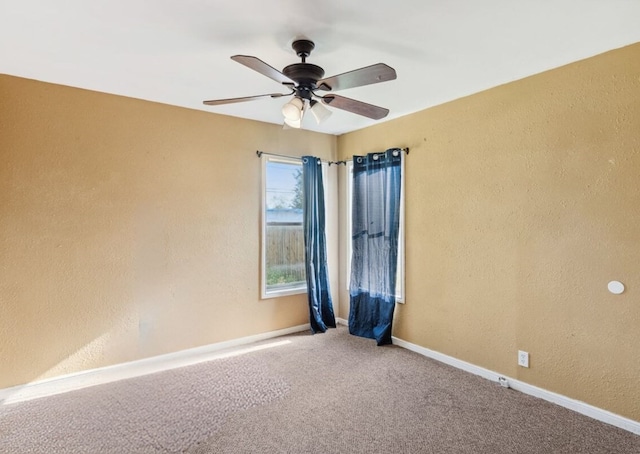 carpeted empty room featuring ceiling fan, baseboards, and a textured wall