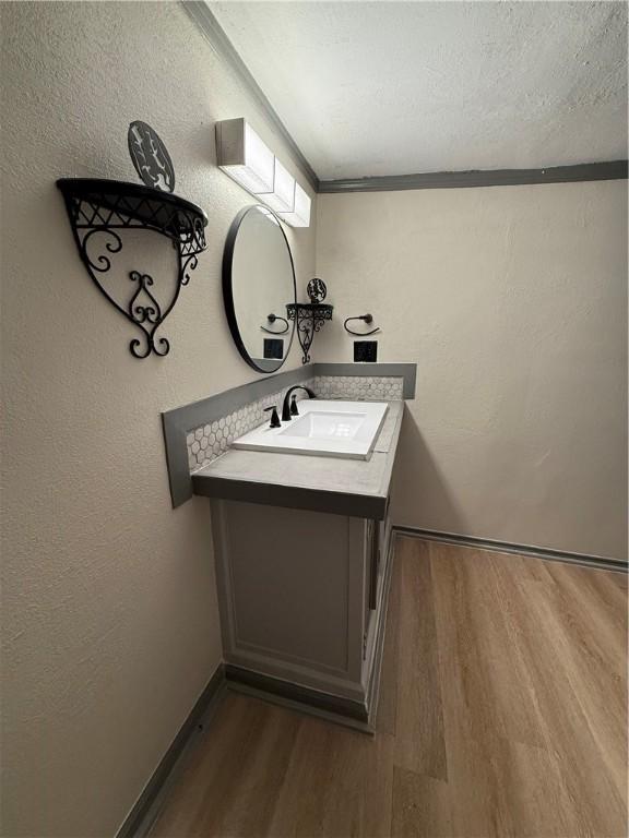 bathroom featuring a textured ceiling, crown molding, hardwood / wood-style floors, and vanity