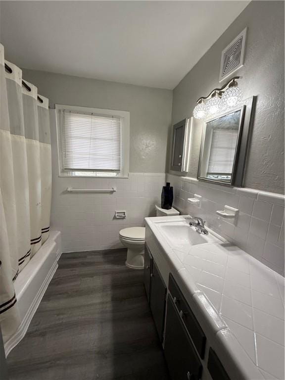 full bathroom with toilet, shower / tub combo with curtain, tile walls, wood-type flooring, and vanity