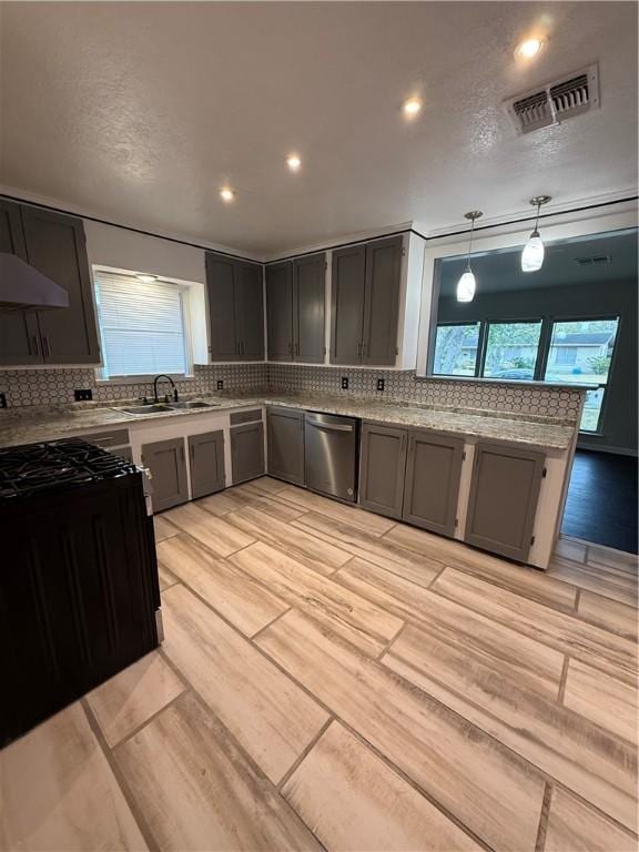 kitchen with pendant lighting, decorative backsplash, sink, light stone counters, and stainless steel dishwasher