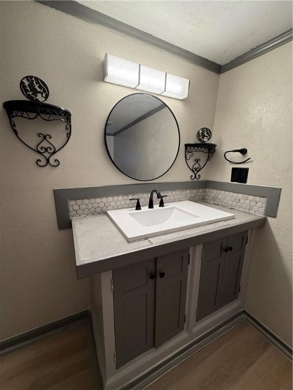 bathroom featuring vanity, ornamental molding, and hardwood / wood-style floors