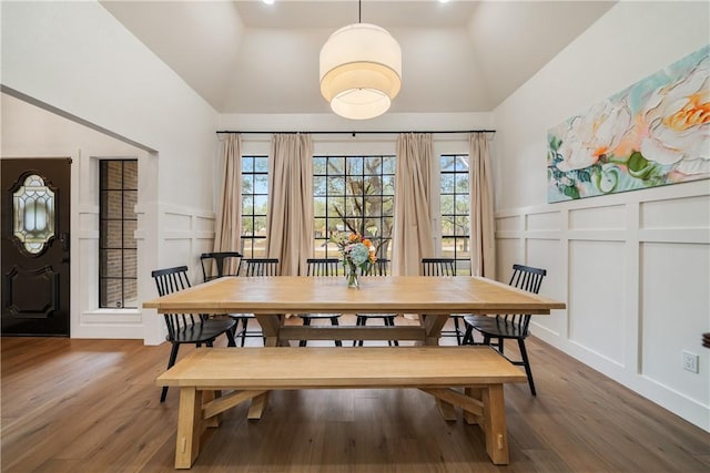 dining space with lofted ceiling, a decorative wall, and dark wood-style flooring