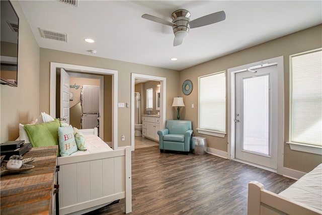 bedroom featuring multiple windows, dark hardwood / wood-style flooring, ceiling fan, and connected bathroom