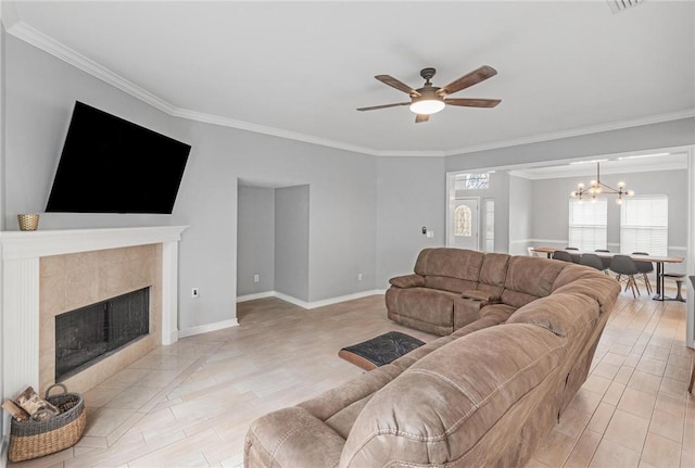 living room with ceiling fan with notable chandelier, light hardwood / wood-style floors, ornamental molding, and a fireplace