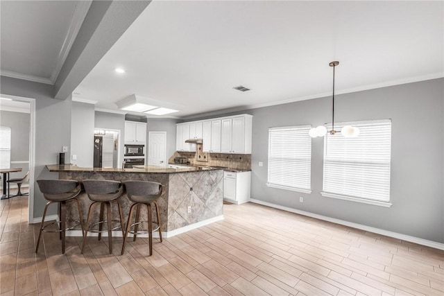 kitchen with white cabinetry, black microwave, and light hardwood / wood-style flooring