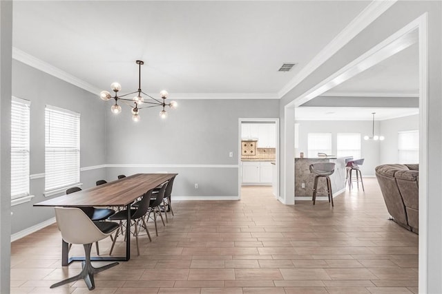 dining area featuring a healthy amount of sunlight, ornamental molding, and a chandelier