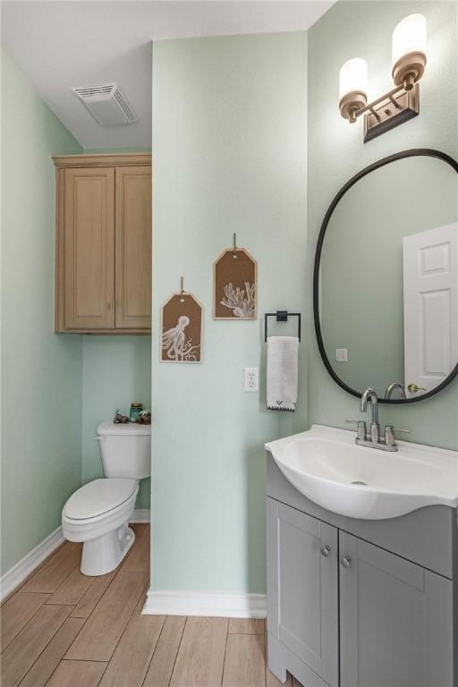 bathroom with toilet, vanity, and hardwood / wood-style flooring