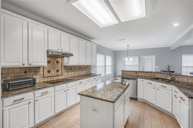 kitchen with a kitchen island, hanging light fixtures, dark stone counters, and sink