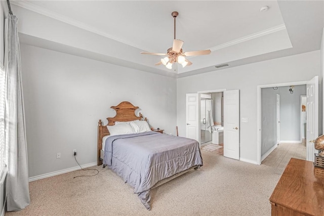 carpeted bedroom featuring a tray ceiling, ensuite bath, and ceiling fan