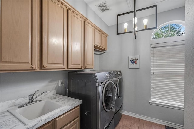 washroom featuring washing machine and clothes dryer, sink, cabinets, and light hardwood / wood-style flooring