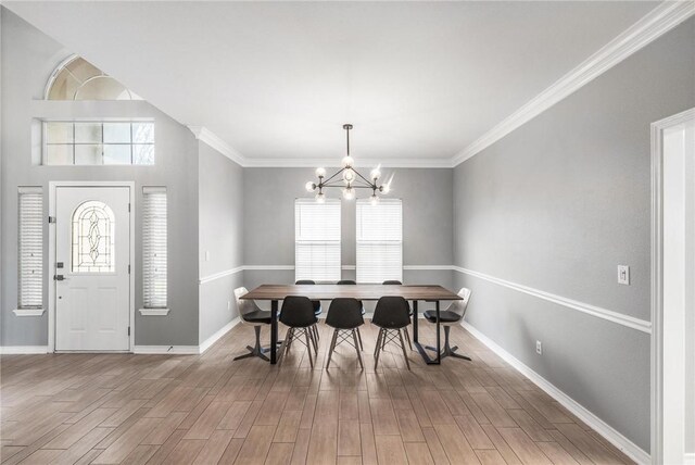 dining room featuring hardwood / wood-style floors, ornamental molding, and a notable chandelier