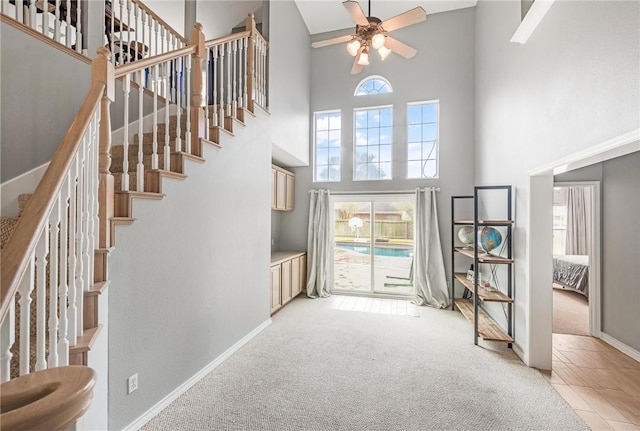 entryway with plenty of natural light, a towering ceiling, and light colored carpet