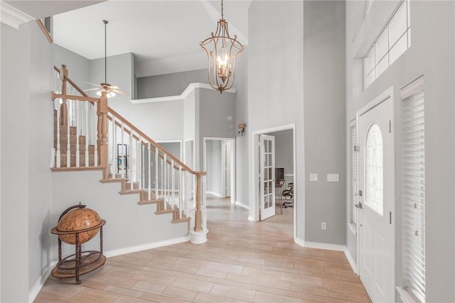 entrance foyer with light hardwood / wood-style flooring, ceiling fan with notable chandelier, and a high ceiling